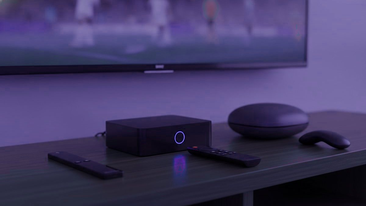 A streaming stick, a set-top box and their remotes on a TV console