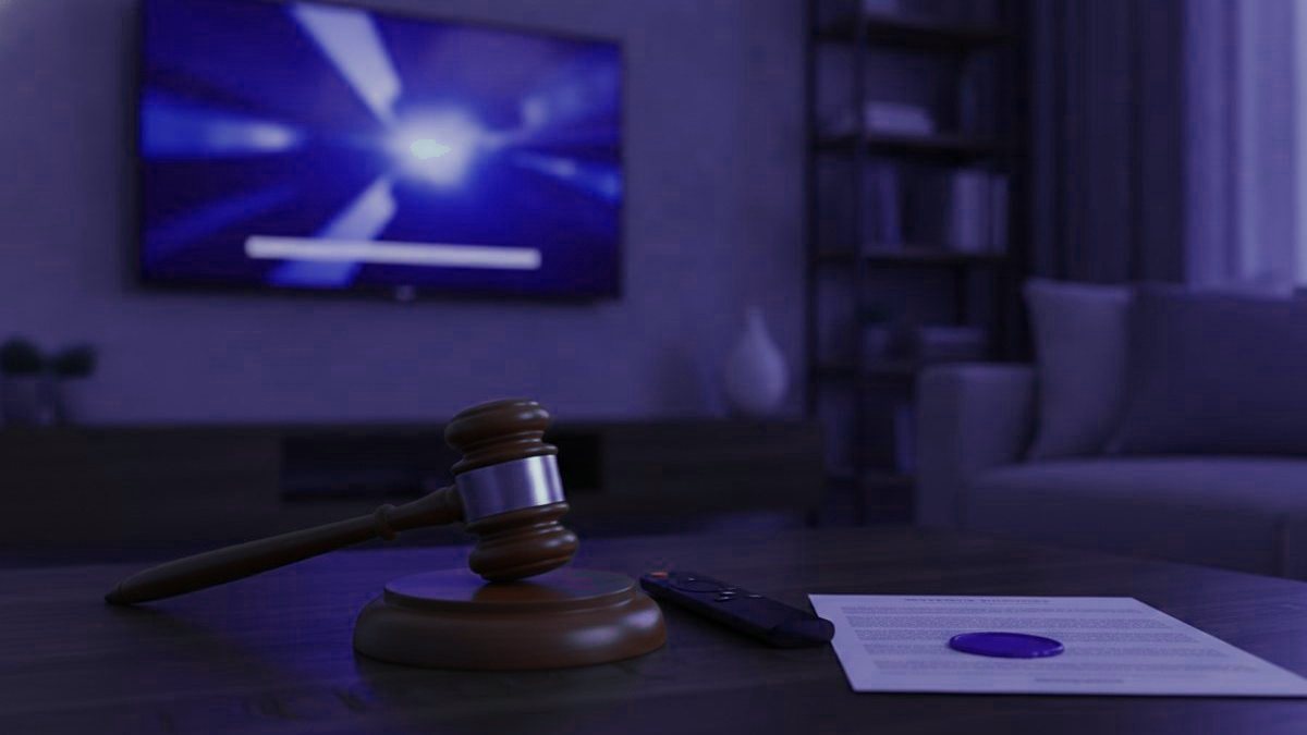 A remote and a sealed document on a table in front of a TV showing a channel guide
